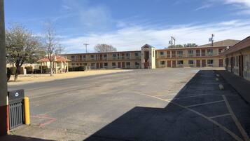A motel with a large parking lot, a central entrance, and multiple motel rooms.