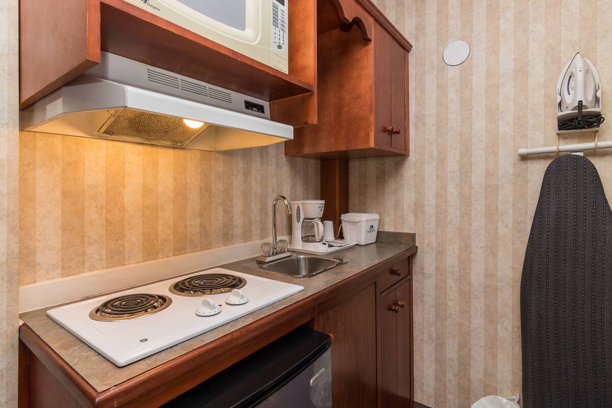 Une petite cuisine équipée avec une cuisinière, un four à micro-ondes, un évier et une machine à café.
