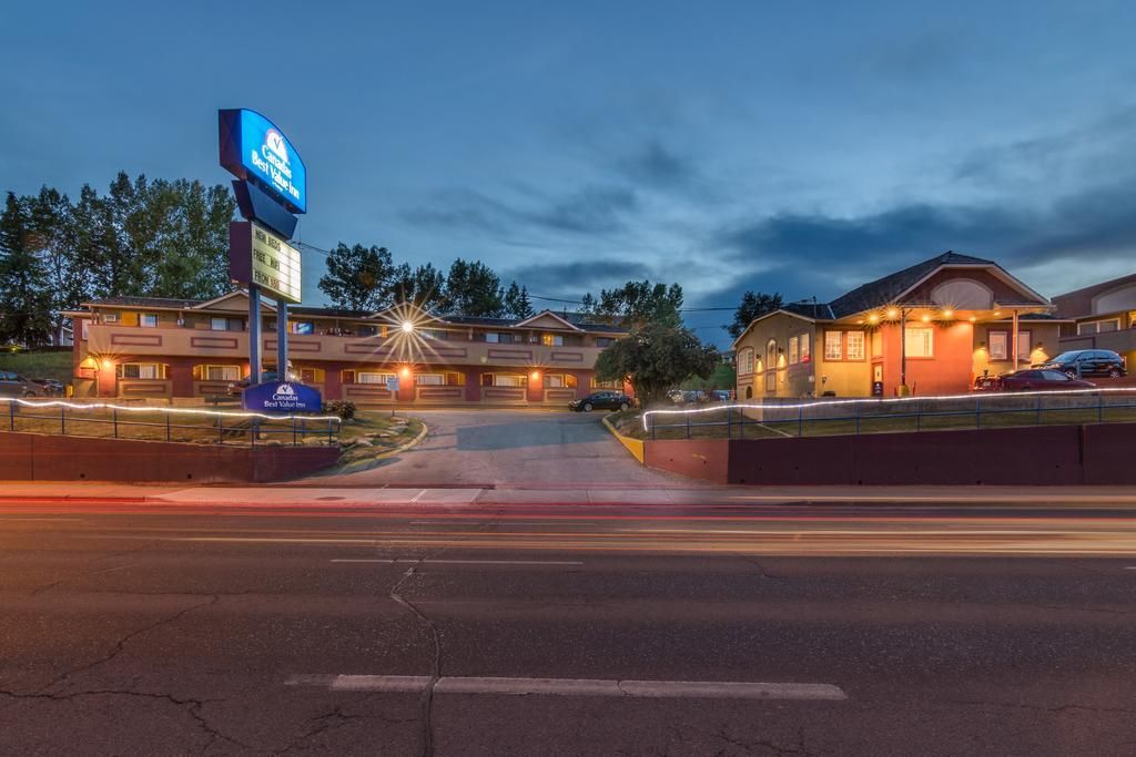 A hotel with a large sign, multiple buildings, and a parking lot.