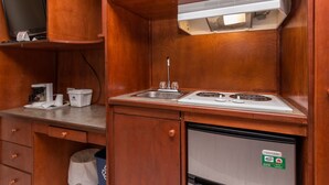 A compact kitchenette with a stove, sink, and a small refrigerator.