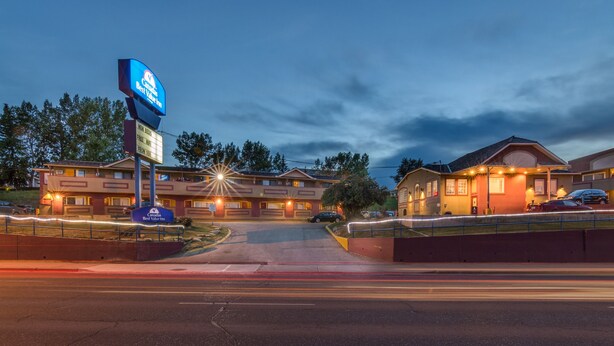 A hotel with a large sign, multiple parking spaces, and a well-lit entrance.