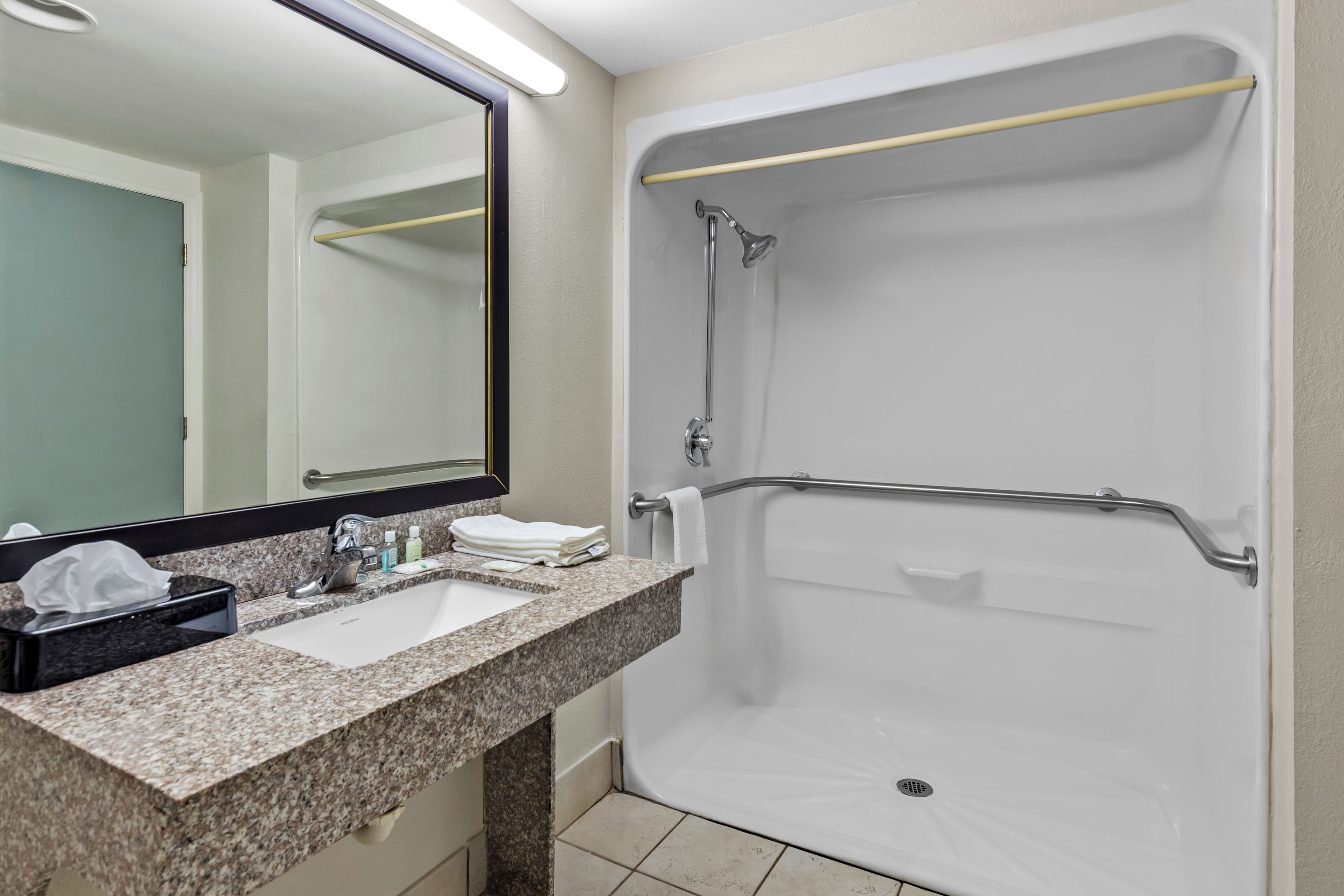 A bathroom with a sink, mirror, and shower.