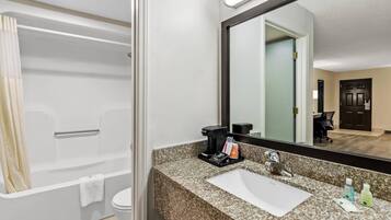 A modern bathroom with a bathtub, a sink with toiletries, and a large mirror.