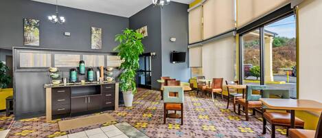 Een moderne hotellobby met een groot raam, een receptiebalie en een kamerbreed tapijt met dessin.