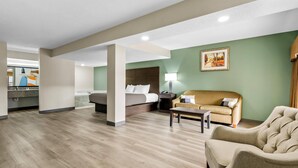 A hotel room with a bed, a sofa, a coffee table, and a desk with a lamp. - Quality Inn Hillsville (Hillsville)