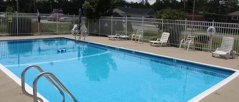 Une piscine rectangulaire avec une échelle métallique située sur le côté gauche.