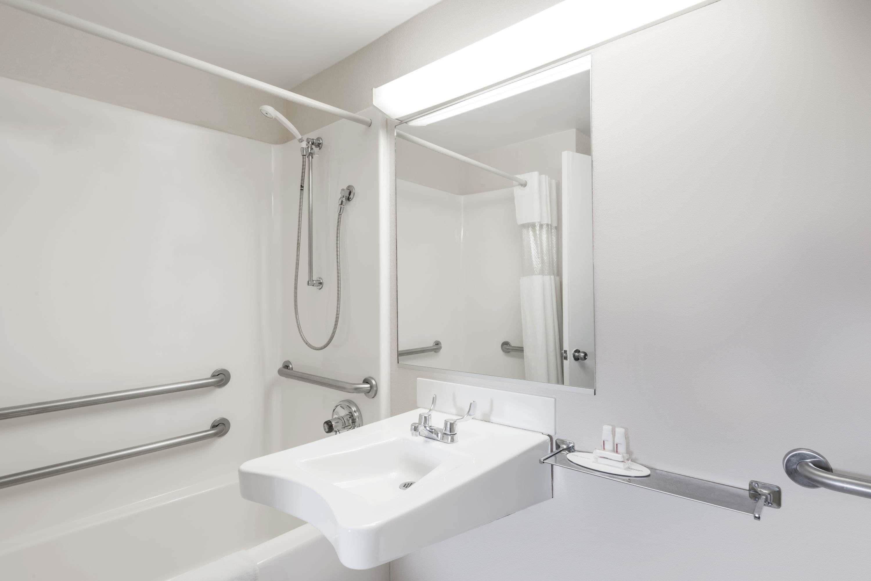 A modern bathroom with a white sink, a mirror, and a shower area.