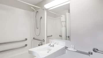 A modern bathroom with a white sink, a mirror, and a shower area.