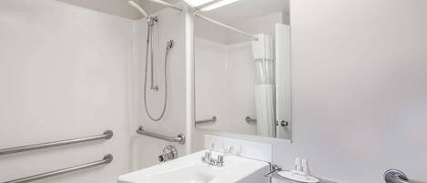 Un baño moderno con un lavamanos blanco, un espejo y una zona de ducha.
