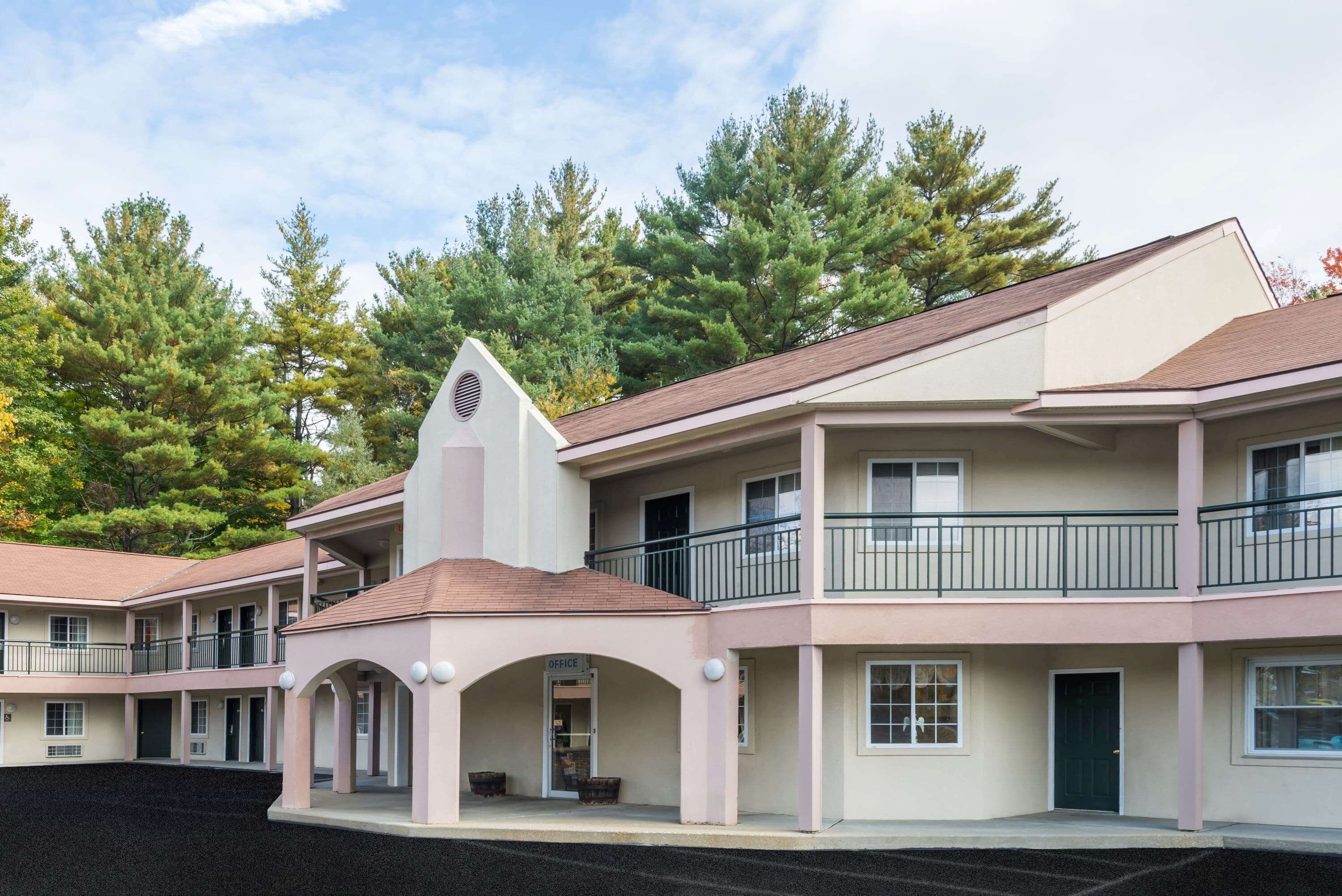 A multi-story building with a central office, balconies, and a parking lot.