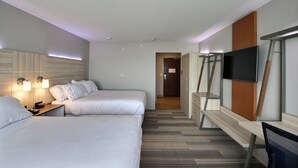 Une chambre d’hôtel avec deux lits, un bureau, une télévision et une armoire.