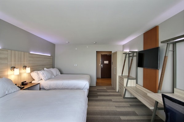 Quarto de hotel com duas camas, uma escrivaninha, televisão e guarda-roupa.