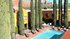 A pool area with lounge chairs, a swimming pool, and tall cypress trees. - Holiday Inn Express Sedona by IHG (Sedona)
