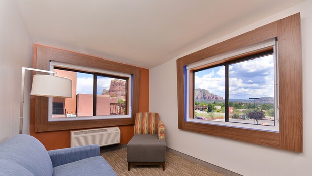 A hotel room with a large window, a sofa, an ottoman, and a lamp. - Holiday Inn Express Sedona by IHG (Sedona)