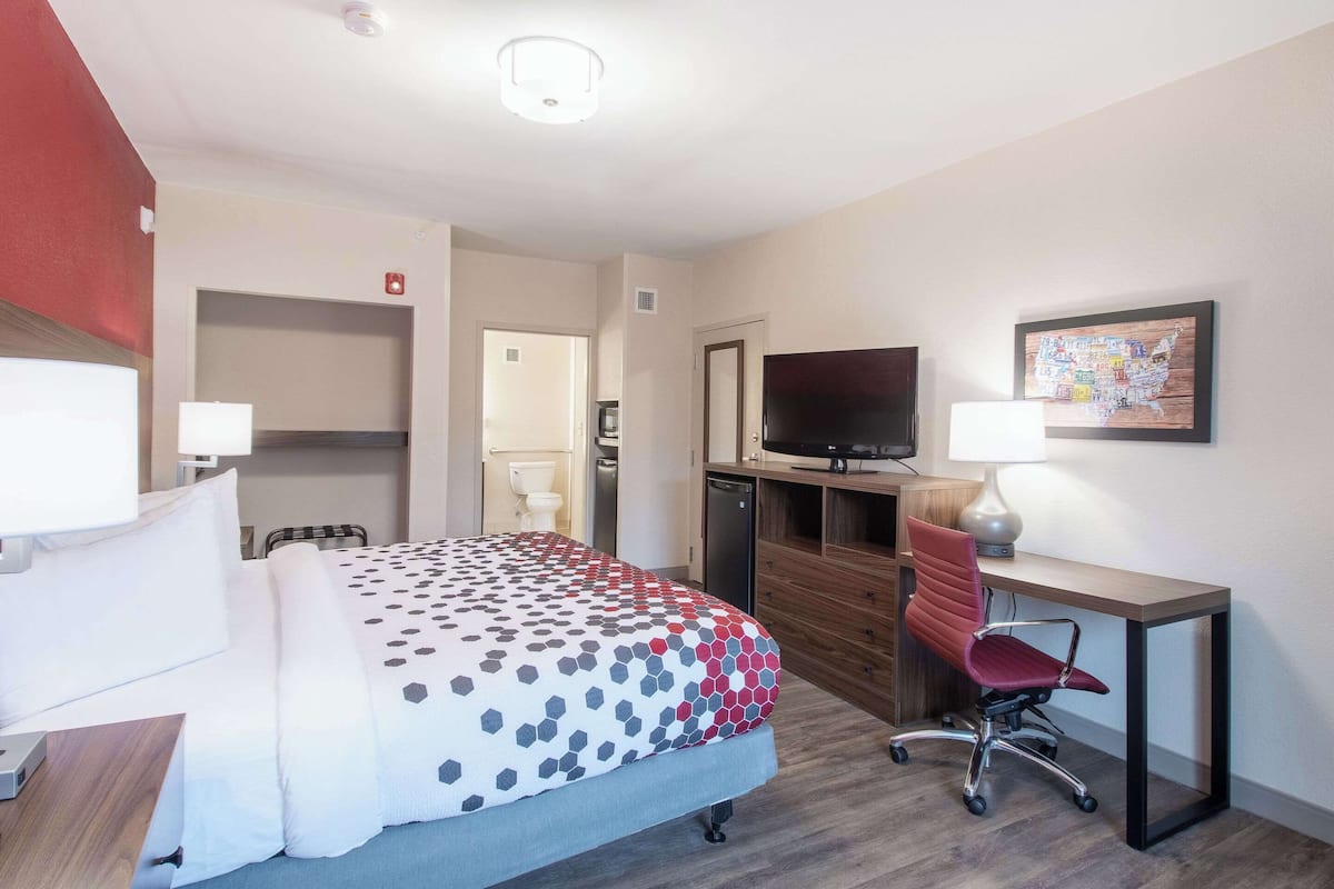 Een hotelkamer met een bed, bureau, stoel, televisie en een kaart aan de muur.