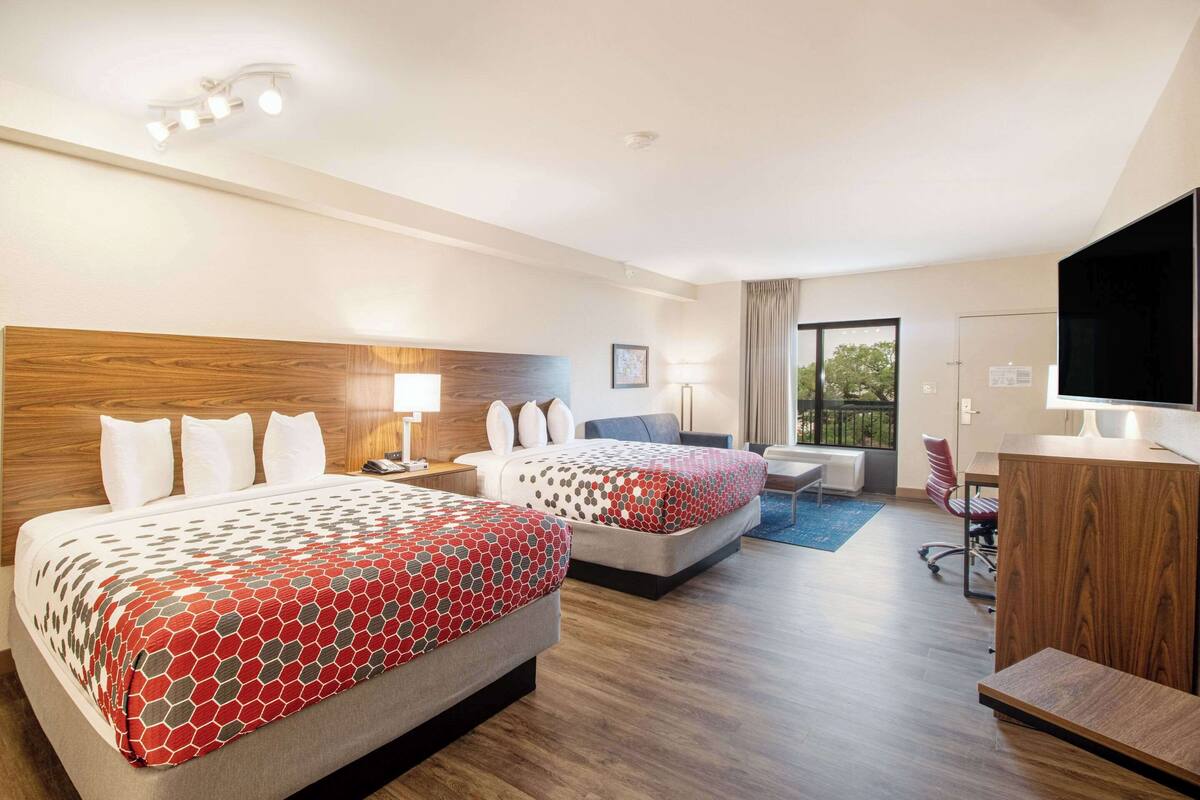 Een hotelkamer met twee bedden, een bureau, een stoel, een televisie en een kledingkast.