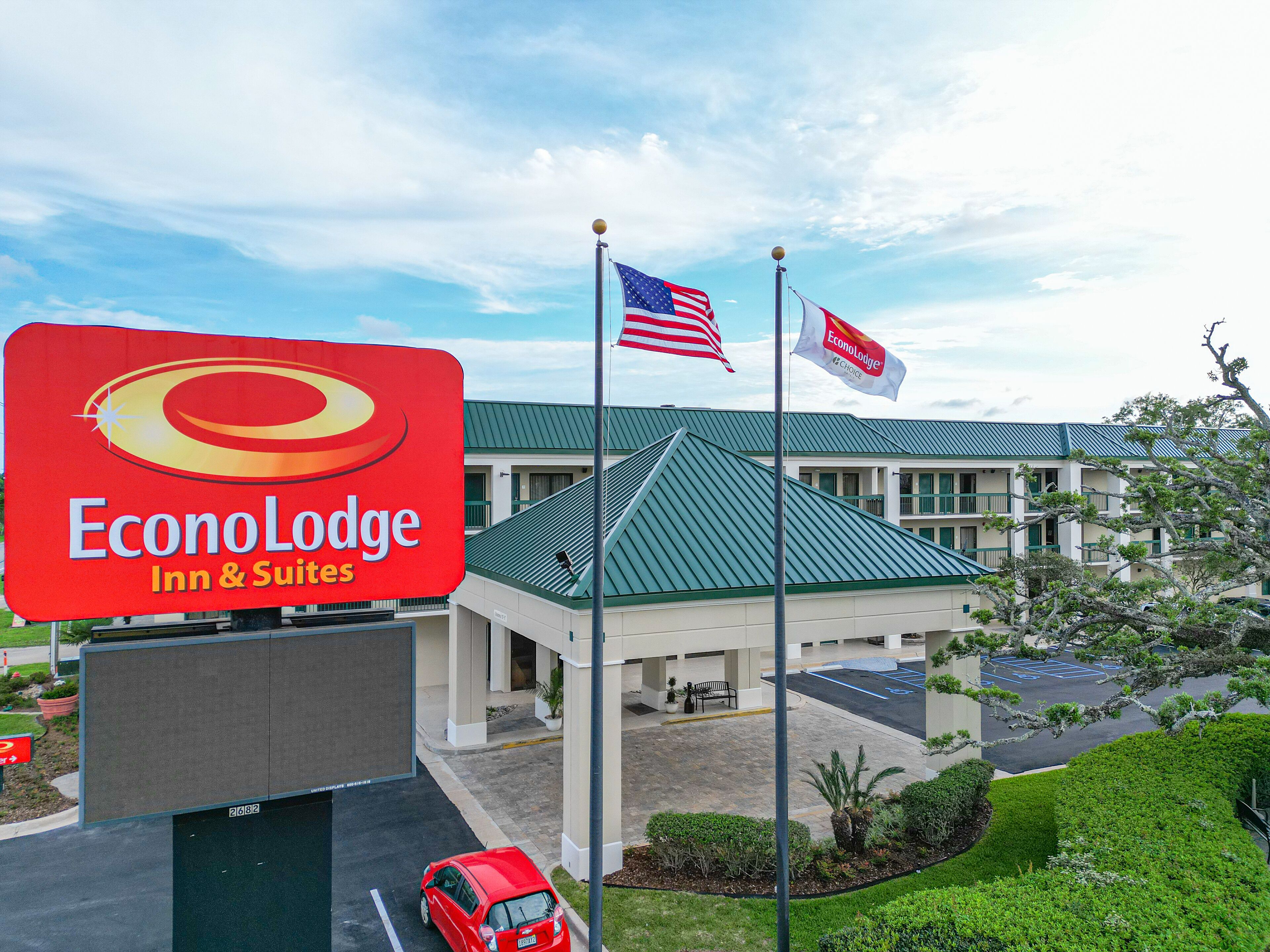 Segnaletica di un hotel EconoLodge Inn & Suites, con un edificio a tetti verdi sullo sfondo.
