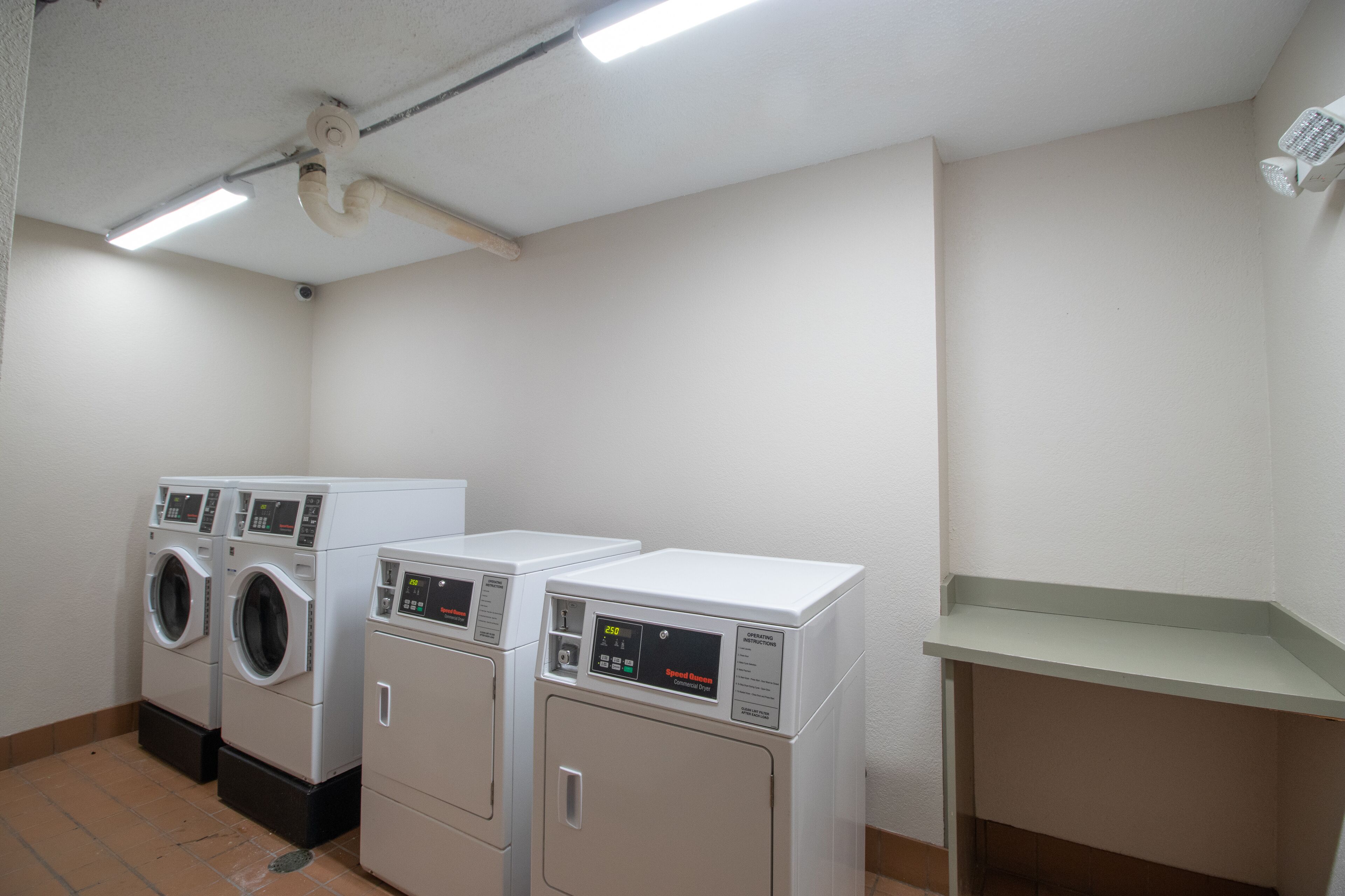 A laundry room with three stacked washers and dryers, a ceiling fan, and a light fixture.