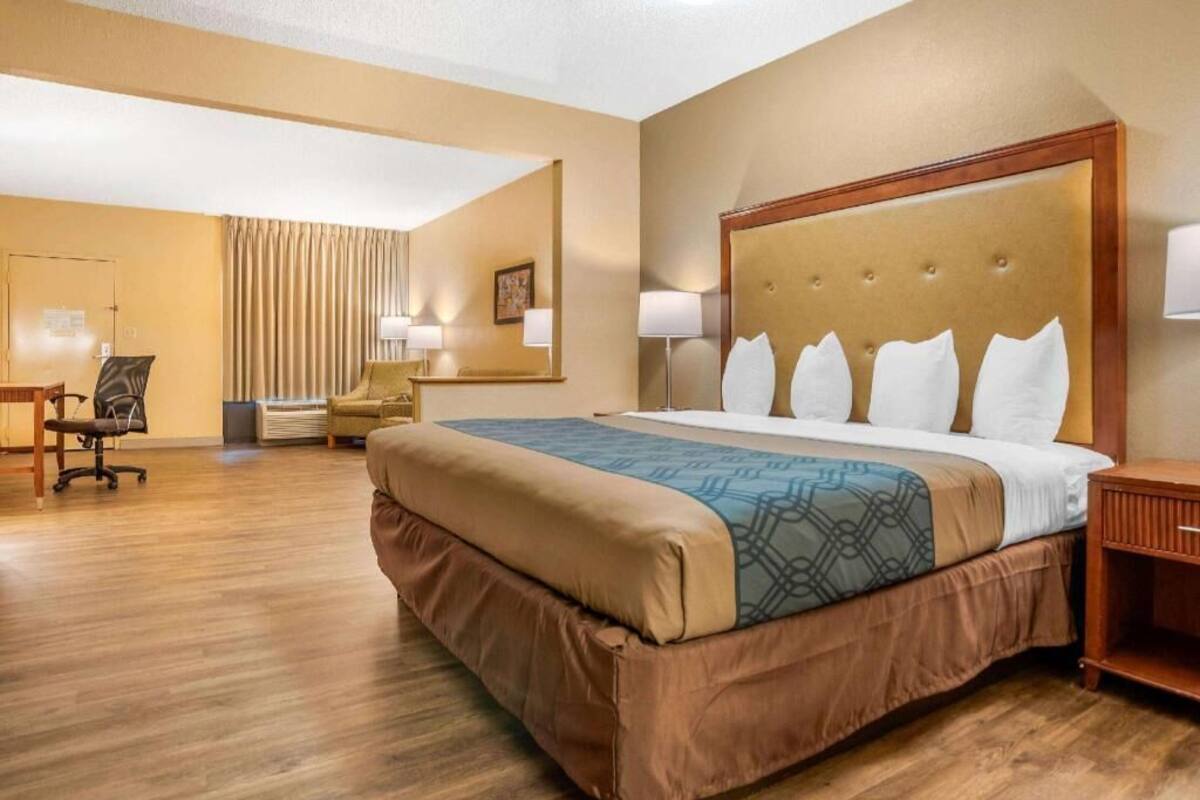Een hotelkamer met een groot bed, een bureau, een stoel en een lamp.