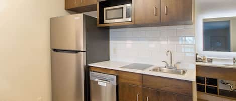 Una cocina moderna con electrodomésticos de acero inoxidable, armarios de madera y salpicadero de azulejos blancos.