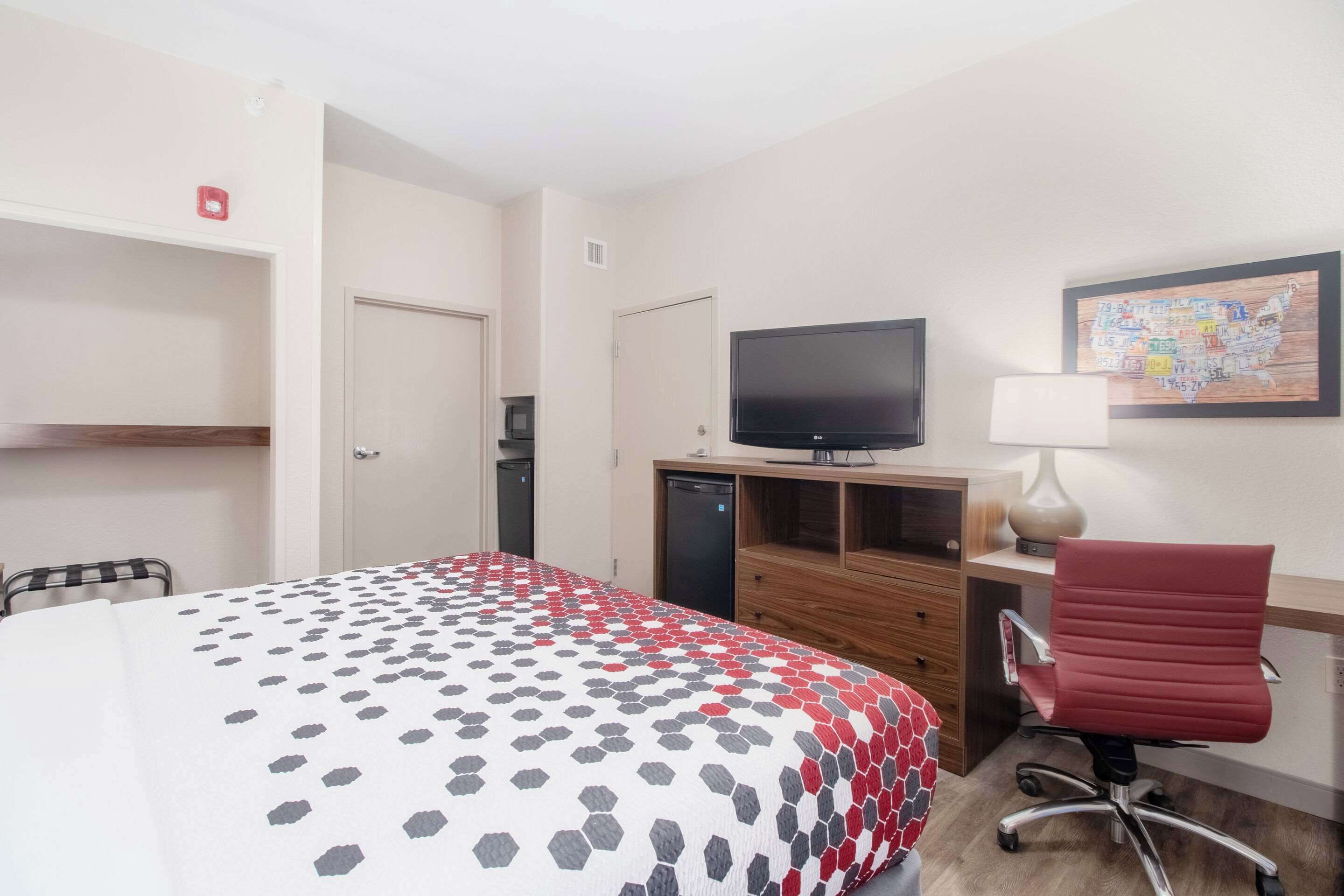Une chambre d’hôtel avec un lit, un bureau avec un ordinateur, une télévision et une chaise.