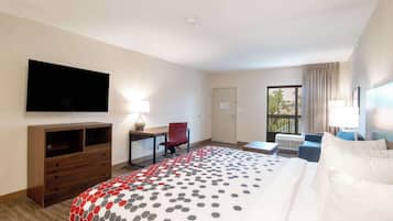 Une chambre d’hôtel avec un grand lit, un bureau avec une chaise, un téléviseur à écran plat fixé au mur et une fenêtre avec des rideaux.