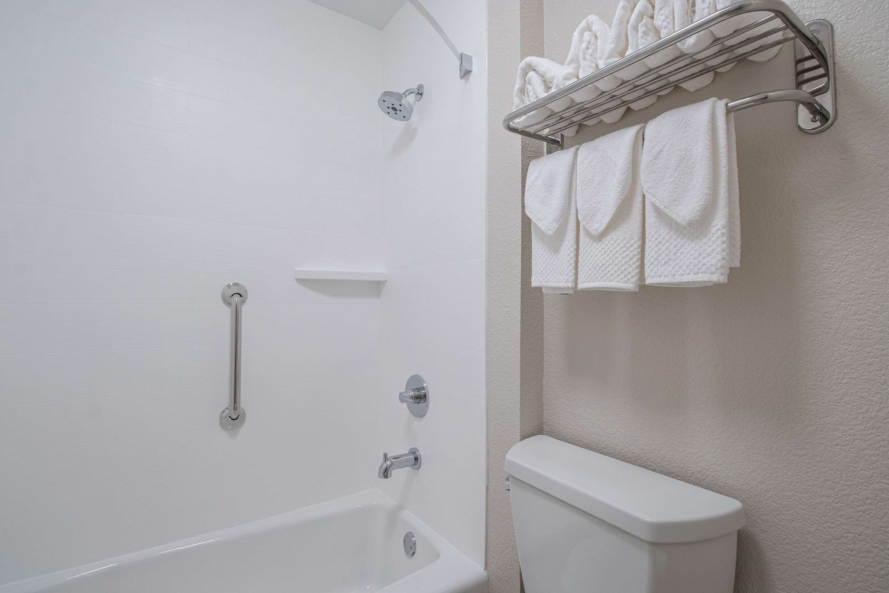A bathroom with a bathtub, a toilet, and a towel rack with towels.