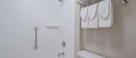 A bathroom with a bathtub, a toilet, and a towel rack with towels.