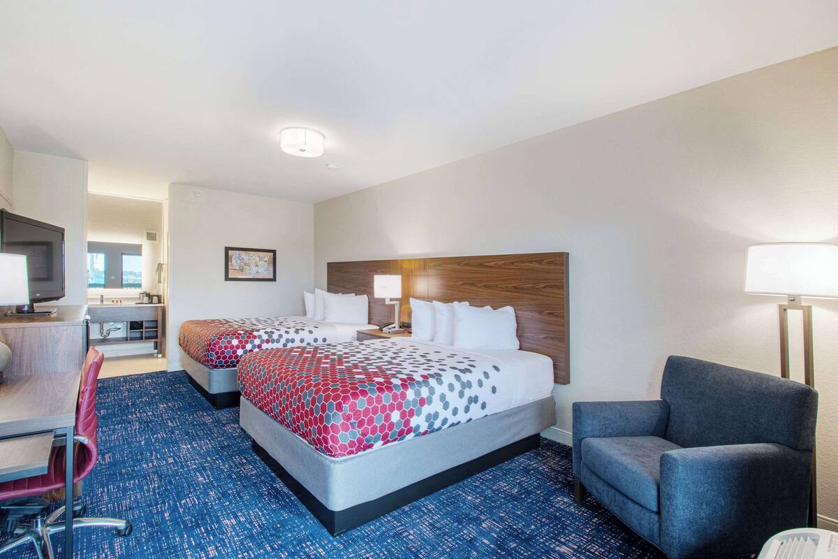 Een hotelkamer met twee bedden, een bureau, een stoel en een televisie.