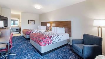 A hotel room with two beds, a desk, a chair, and a TV.