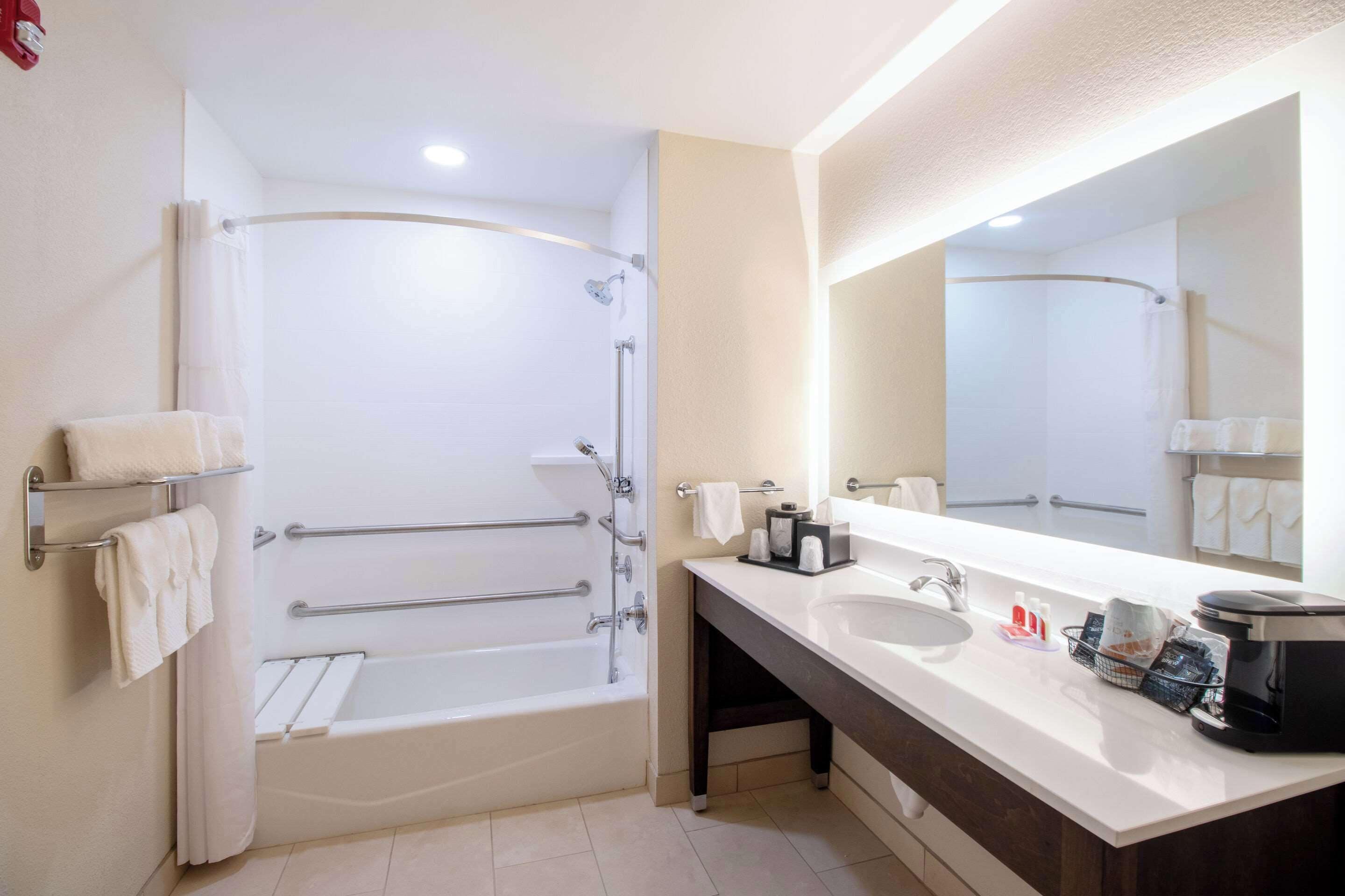 A modern bathroom with a bathtub, a sink, and a large mirror.