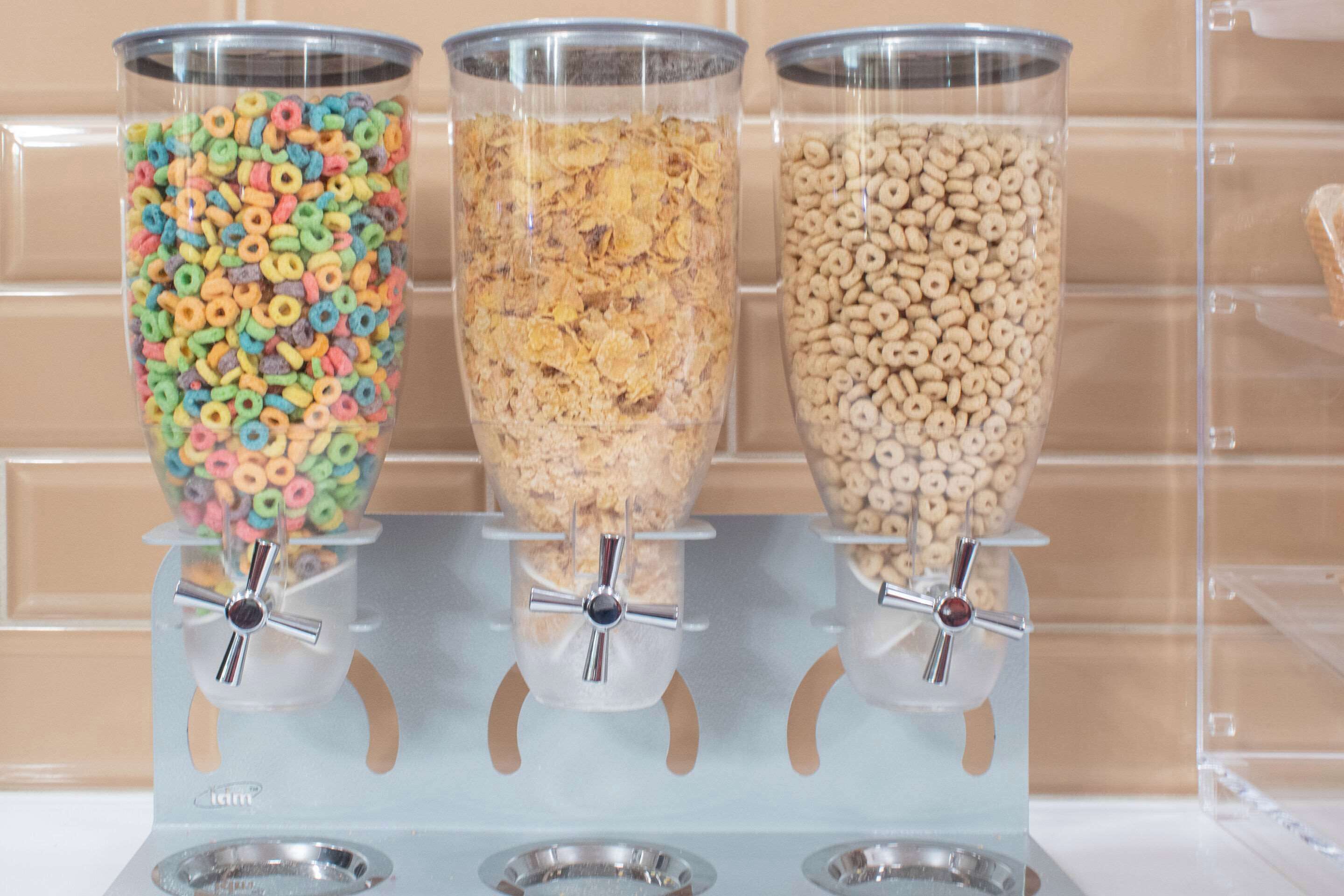 Três dispensadores com diferentes tipos de cereal.
