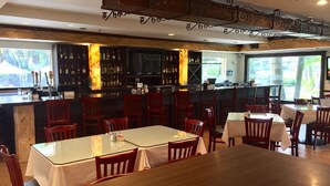 A restaurant with a bar area, wooden tables, and chairs. - Grand Palms Spa & Golf Resort (Pembroke Pines)