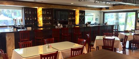 Un restaurant doté d’un bar, de tables et de chaises en bois.