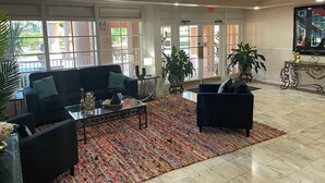 A spacious lobby with a black sofa, a coffee table, and a patterned rug. - Grand Palms Spa & Golf Resort (Pembroke Pines)