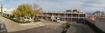 Un edificio moderno con área de estacionamiento techada, una escalera y una vista de montaña al fondo.