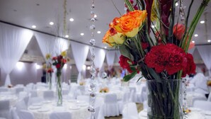 A banquet hall with round tables covered in white tablecloths and floral centerpieces.