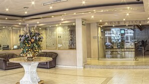 A lobby with a round table, leather sofas, and a bar area.
