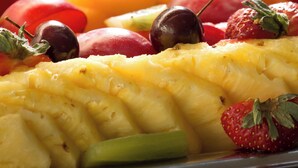 Un plateau contenant un assortiment de fruits, notamment des fraises, des cerises et des tranches d’ananas.