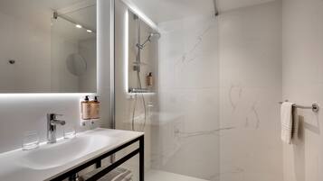 Un baño moderno con lavamanos, espejo y ducha blancos.
