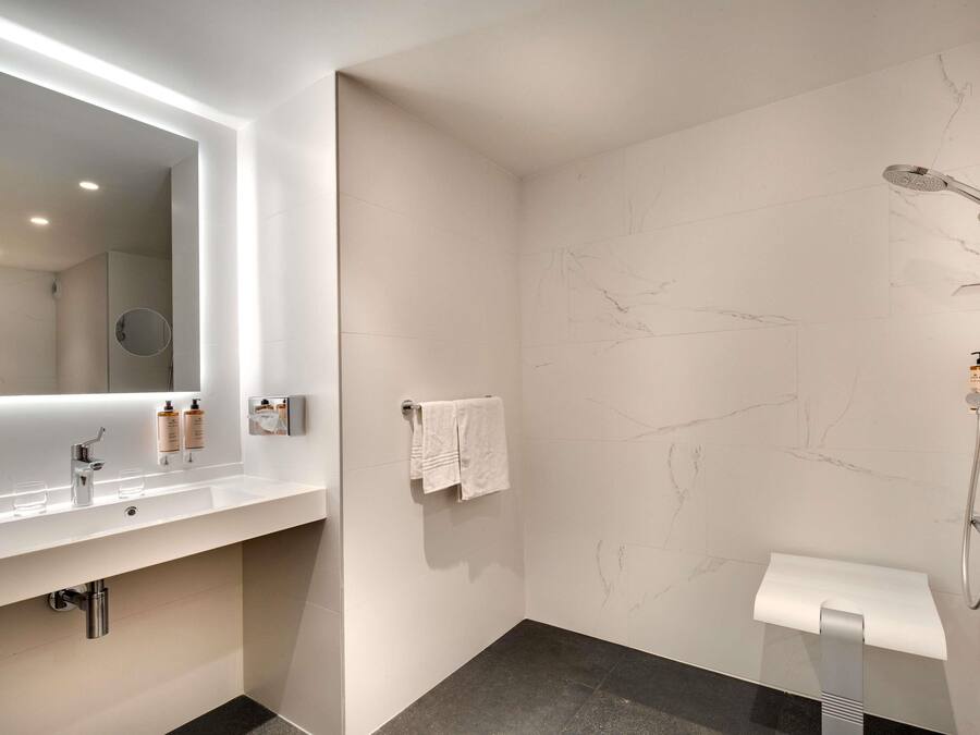 Un bagno moderno con uno specchio grande, una doccia e un water.