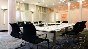 A conference room with a long table, black chairs, and glass partitions. - Mercure Montpellier Centre Antigone (Montpellier)