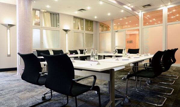 A conference room with a long table, black chairs, and glass partitions. - Mercure Montpellier Centre Antigone (Montpellier)