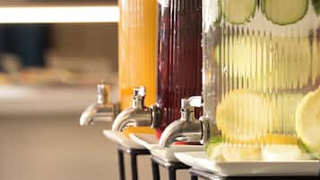 A beverage dispenser with multiple drink options and a row of glasses below.