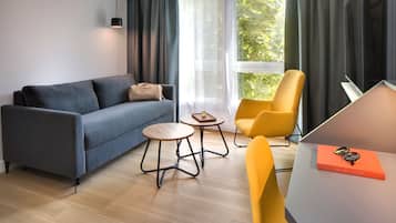 Una sala moderna con un sofá gris, un sillón amarillo, una mesita de madera y un televisor sobre un mueble.