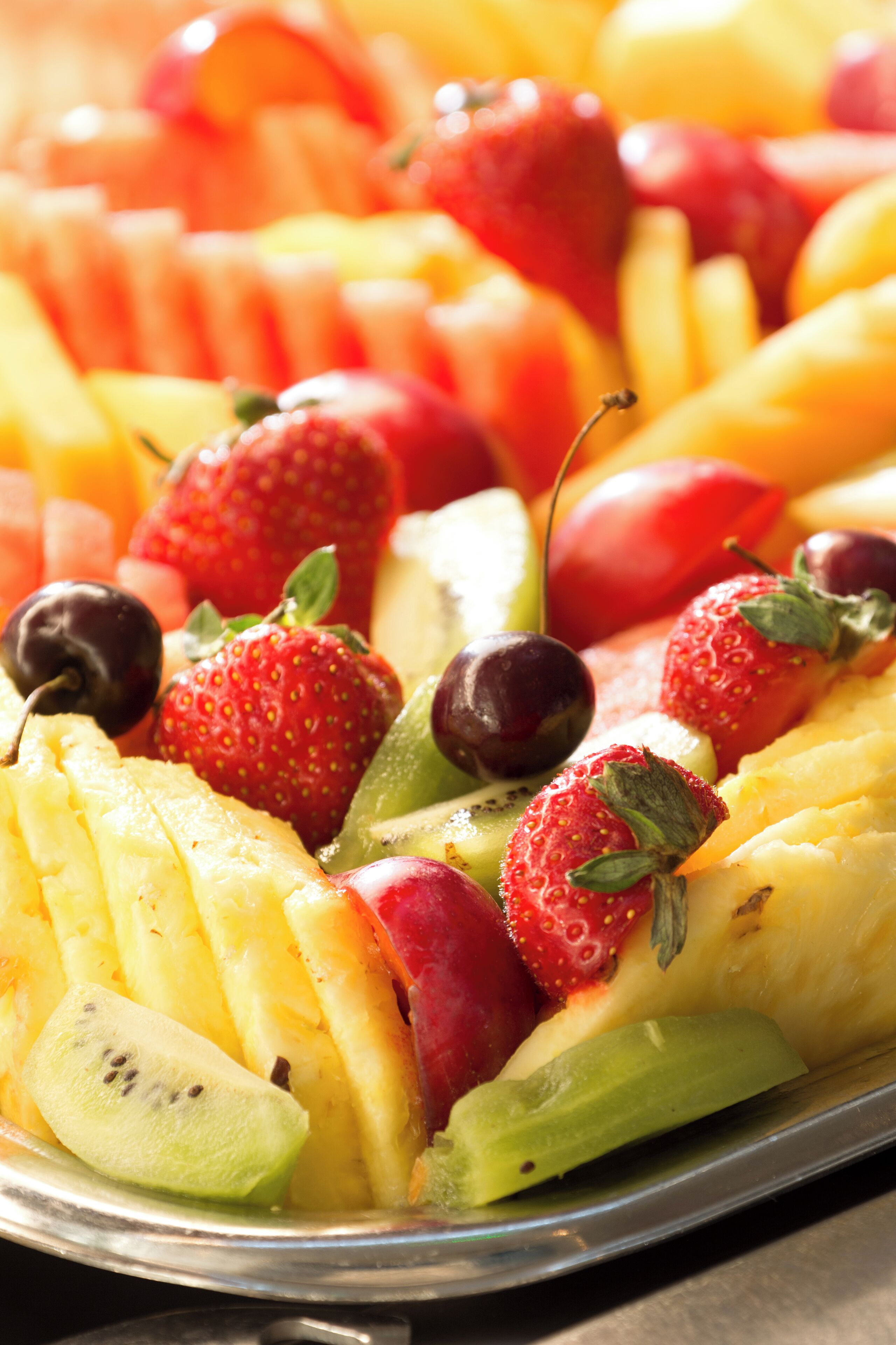 A variety of fresh fruits including strawberries, kiwis, and bananas arranged on a tray.