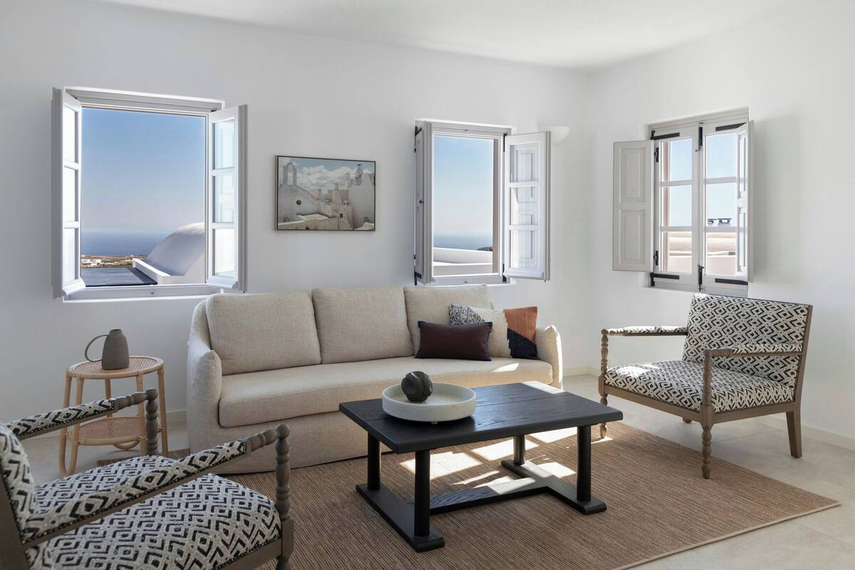 A living room with a sofa, two patterned chairs, a coffee table, and a painting on the wall.