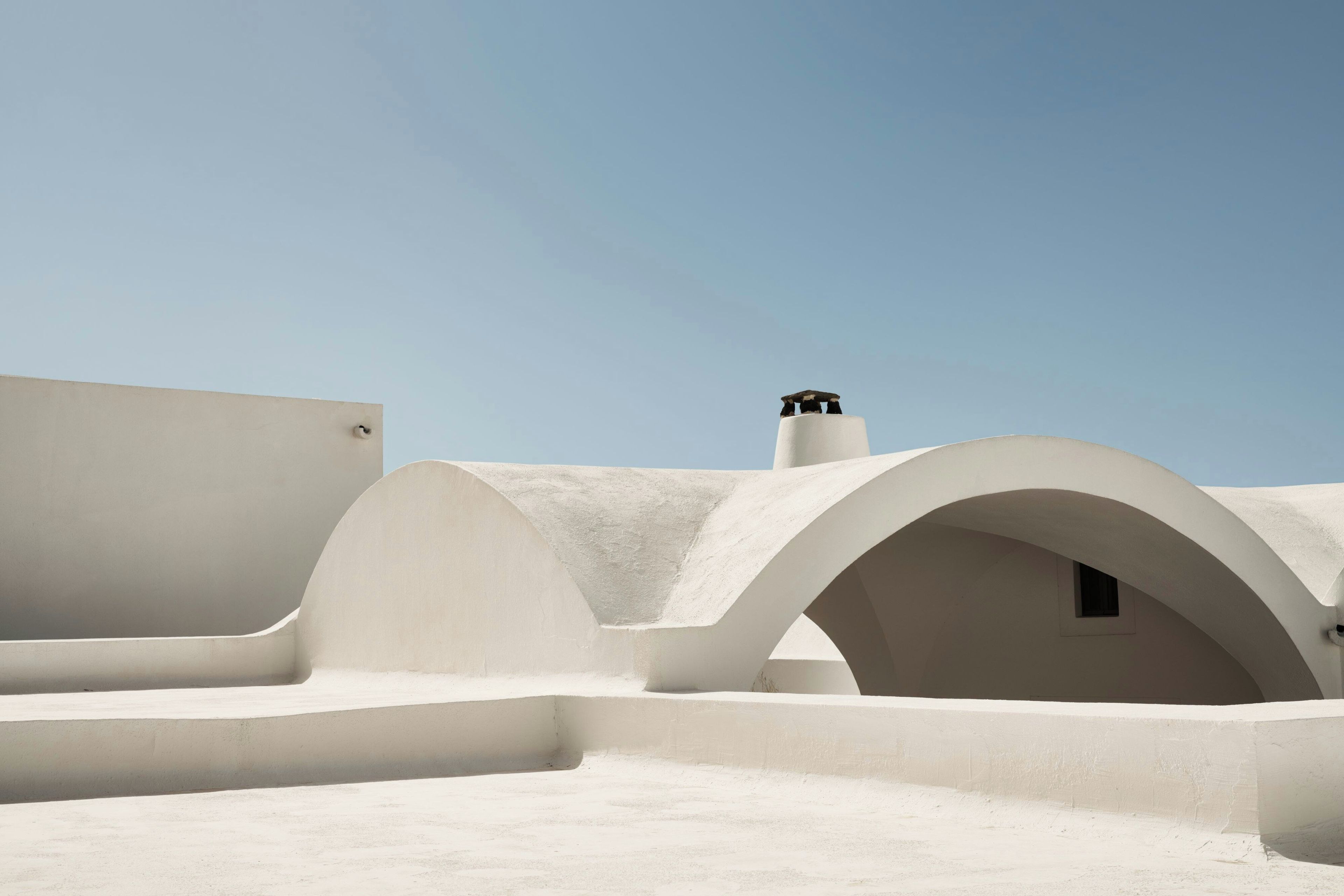Un edificio bianco con strutture ad arco e un camino.