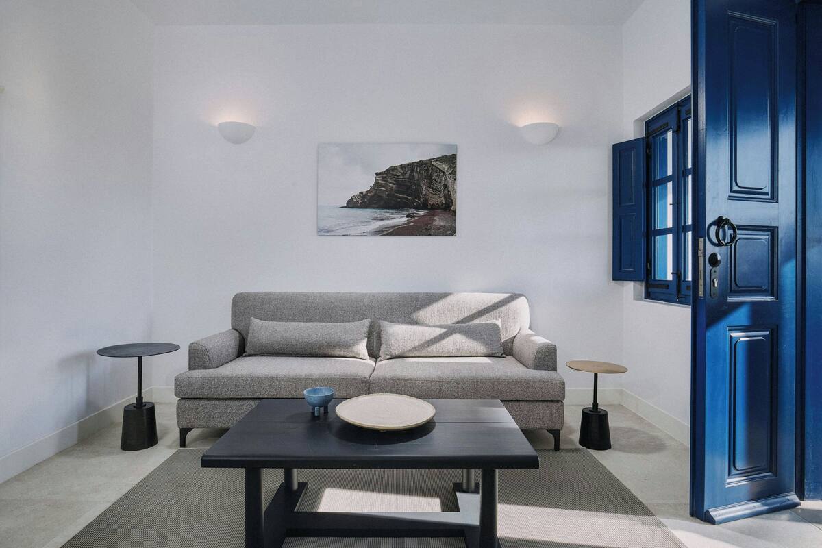 A modern living room with a grey sofa, a round coffee table, and a blue door.