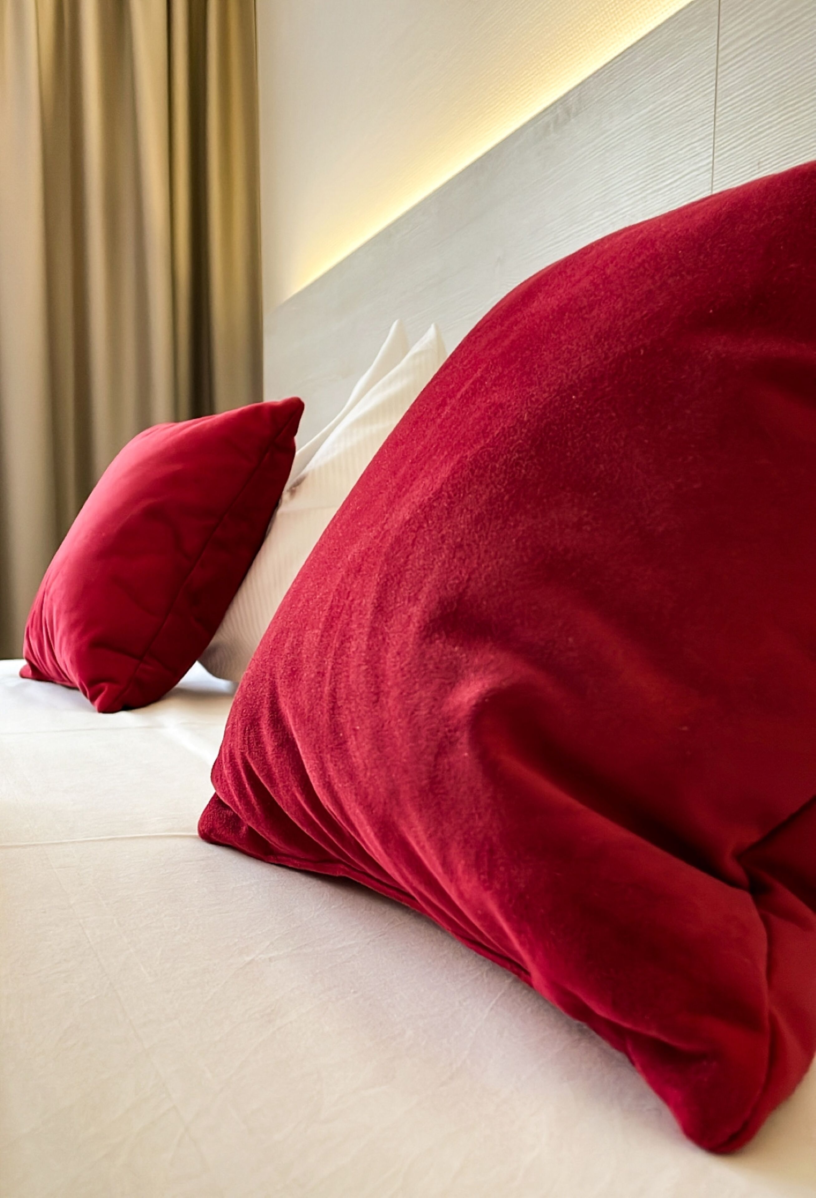 Een bed met twee rode kussens en een wit hoofdeinde.
